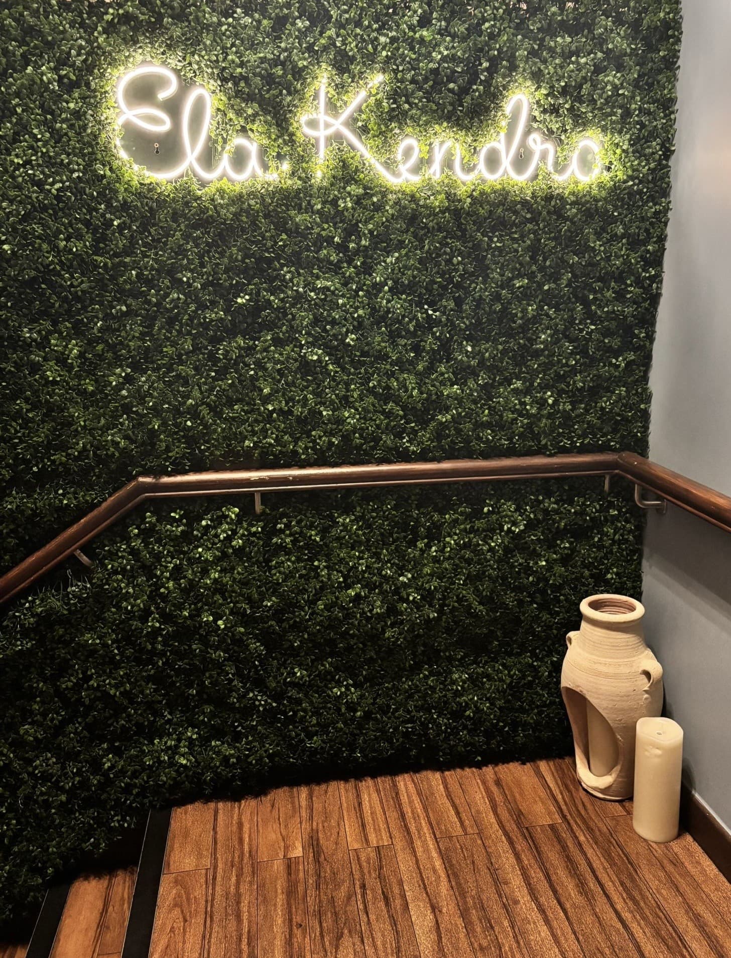Ela Kendro neon sign on the foliage wall